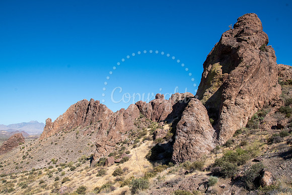 Sharp desert rock formations in Arizona with golden grass and clear blue sky in the background