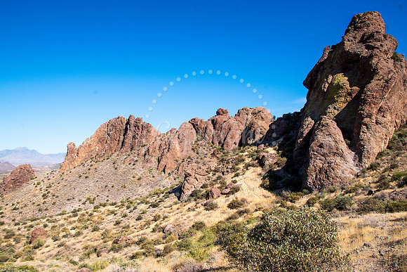 Dramatic Arizona desert ridgeline with red rock formations and dry golden grass under a deep blue sky